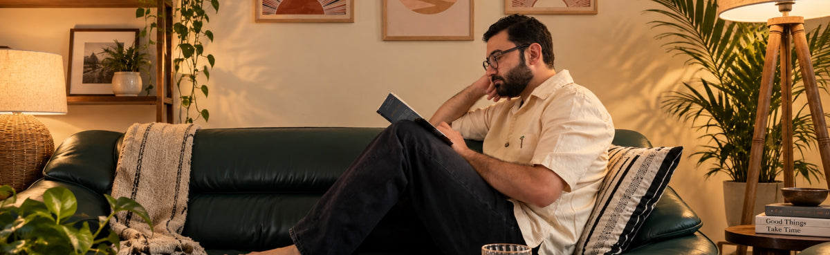 Sanctuary: a man reads on a green sofa with a striped cushion in warm evening light