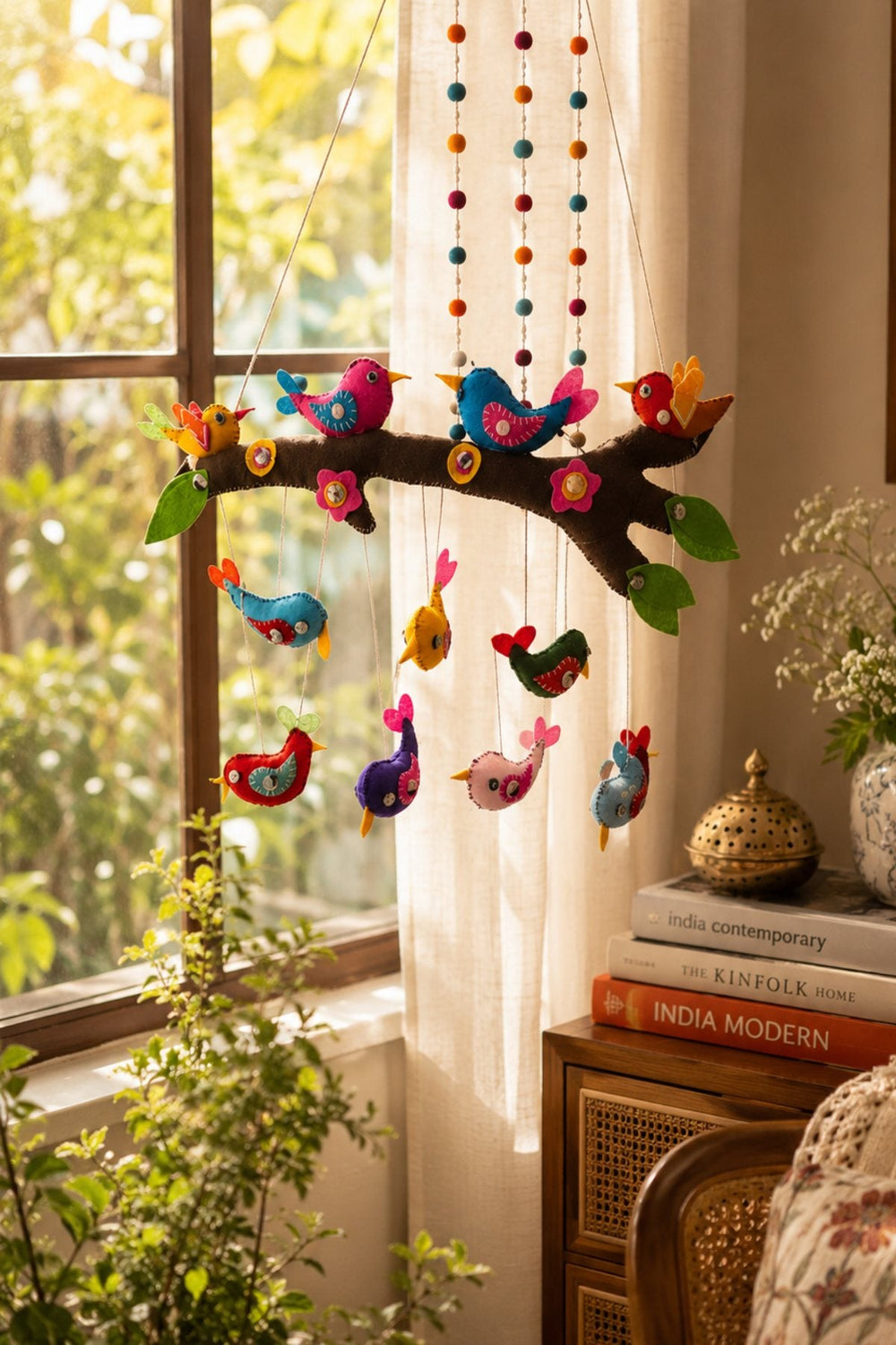 Felt: a hanging branch of colourful felt birds by a sunlit window