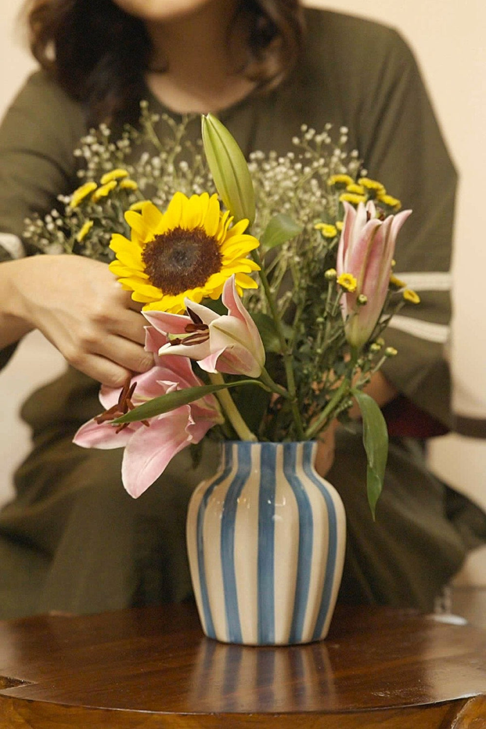 Home Decor: a blue striped vase of sunflowers and lilies on a wooden table