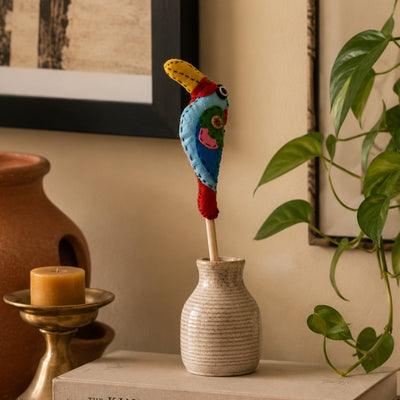 Felt: a colourful wool-felt bird on a stick in a ceramic bud vase