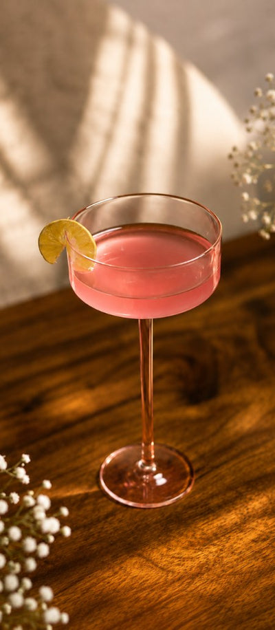 Glassware: a pink drink in a coupe glass on a wooden table